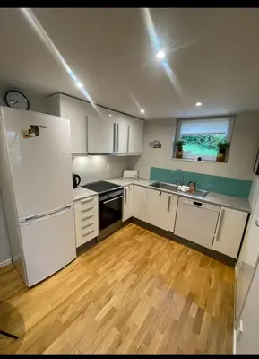 a kitchen with a white refrigerator and a wooden floor at Bingo apartaments in Hønefoss