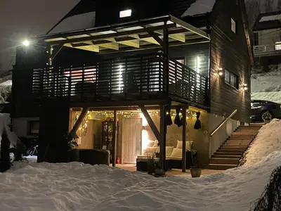 a house with a porch in the snow at night at Bingo apartaments in Hønefoss