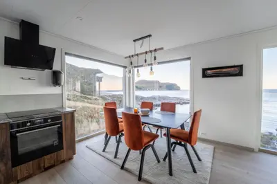 a dining room with a table and chairs with a view of the ocean at Runde Panorama - Østen Pilot in Terøy