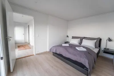 a white bedroom with a large bed and a hallway at Runde Panorama - Østen Pilot in Terøy