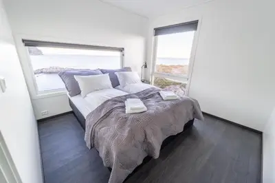 a bedroom with a bed and two large windows at Runde Panorama - Castillo in Terøy