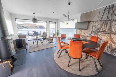 a living room with a table and chairs and the ocean at Runde Panorama - Castillo in Terøy