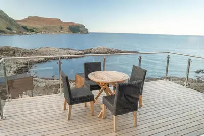 a wooden table and chairs on a deck with the ocean at Runde Panorama - Castillo in Terøy