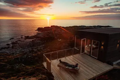 a house on the shore of the ocean with the sunset at Runde Panorama - Batavia Dream in Terøy