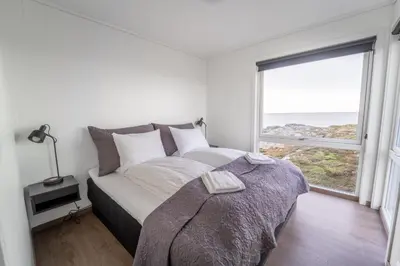 a bedroom with a bed and a large window at Runde Panorama - Batavia Dream in Terøy