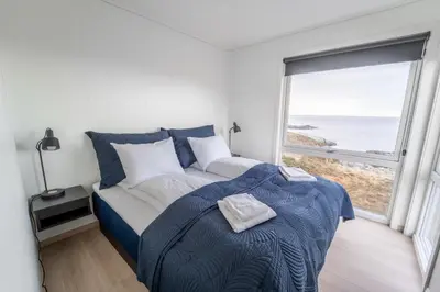 a bedroom with a bed with a view of the ocean at Runde Panorama - Blått Hav in Terøy