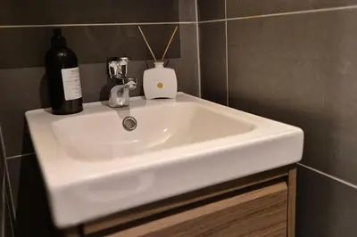 a white sink in a bathroom with a bottle of wine at Luxurious city apartment in Bergen