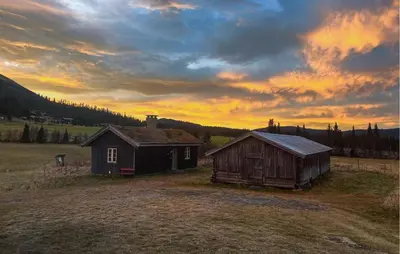 two old barns in a field with a sunset at Stunning Home In Fåvang With Wifi in Favang
