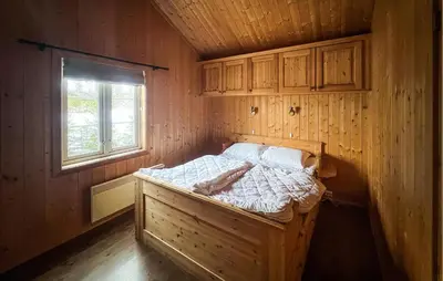 a bed in a wooden room with a window at Cozy Home In Fåvang With Wifi in Favang