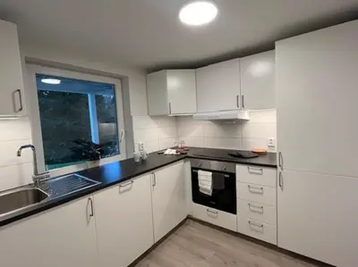 a kitchen with white cabinets and a sink and a window at Apartments near Bergen Airport in Bergen