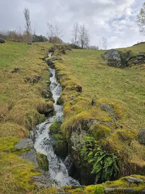 a stream in a field next to a grassy field at Casa Grend in Kvam