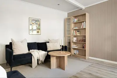 a living room with a black couch and a table at Leilighet i Sandviken in Bergen