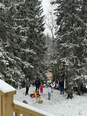a group of people standing around a fire in the snow at Skogshytte på Skreia in Brattlia