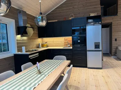 a kitchen with a table and a white refrigerator at Skogshytte på Skreia in Brattlia