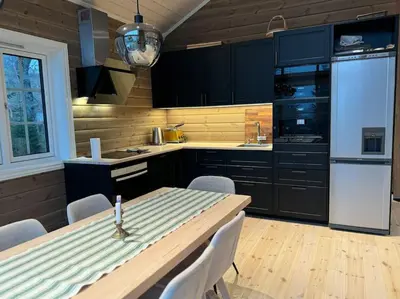 a kitchen with a table with chairs and a refrigerator at Skogshytte på Skreia in Brattlia