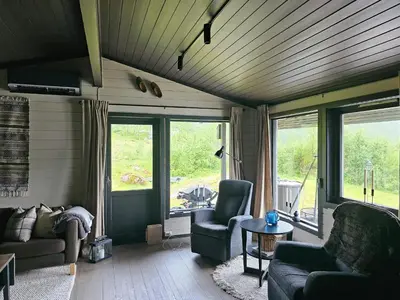 a living room with a couch and chairs and windows at Mountain Cabin With Magical View And Tranquil Lake in Matre