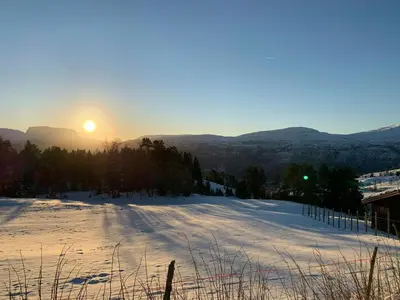 a snowy field with the sun setting in the mountains at Countryside Cabin With Jacuzzi Near Stryn in Sølberg