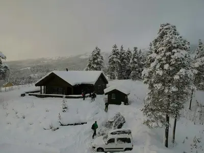 a group of people standing in the snow near a cabin at Countryside Cabin With Jacuzzi Near Stryn in Sølberg