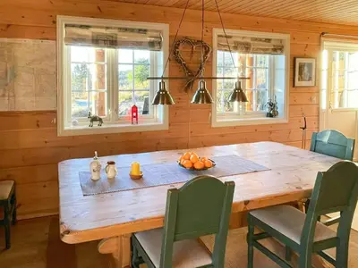 a wooden table in a kitchen with chairs and windows at Countryside Cabin With Jacuzzi Near Stryn in Sølberg