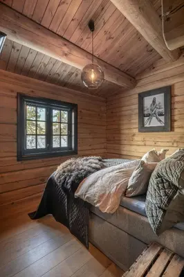 a bedroom with a bed in a room with wooden walls at Modern Log Cabin With Hot Tub And Sauna in Veggli