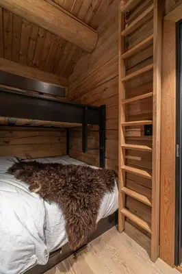 a bed in a wooden room with a wooden wall at Modern Log Cabin With Hot Tub And Sauna in Veggli