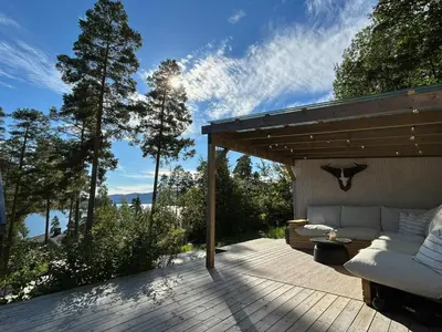 a patio with a couch on a wooden deck at New Cabin By Tyrifjorden For Relaxing Holidays in Gjesval
