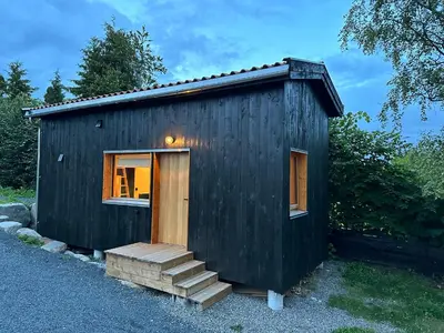 a black tiny house with a door and stairs at Mikrohus i byen - Tinyhouse Hamar city in Hamar