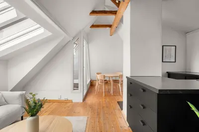 a kitchen and living room in a loft with a table at Bryggen Historical Townhouse I Rooftop Views! in Bergen