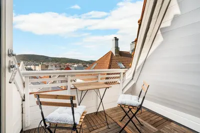 a balcony with two chairs and a view of the city at Bryggen Historical Townhouse I Rooftop Views! in Bergen