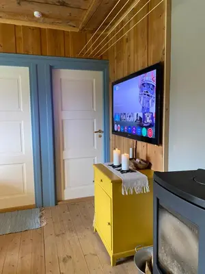 a living room with a flat screen tv on a wall at Brattland Sæter in Strond
