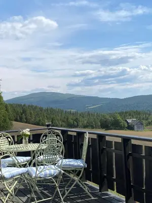 a table and chairs on a deck with mountains in the background at Brattland Sæter in Strond