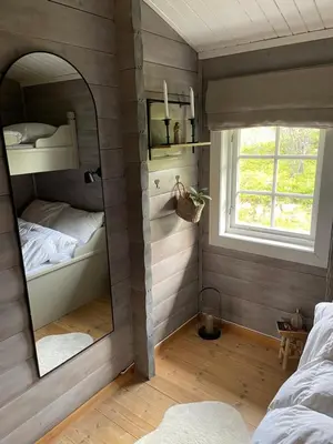 a bedroom with a mirror and a bed and a window at Koselig hytte på Beito in Beitostøl