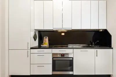 a white kitchen with white cabinets and a sink at 3-roms leilighet i hjertet av Sandviken in Bergen