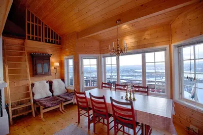 a dining room with a table and chairs and windows at Ski-In Ski-Out Cozy Retreat With Mountain Views in Beitostøl