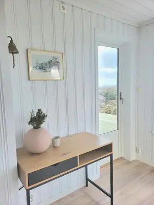 a desk with a vase on it in a room with a window at Stor hytte med fantastisk utsikt in Vikso