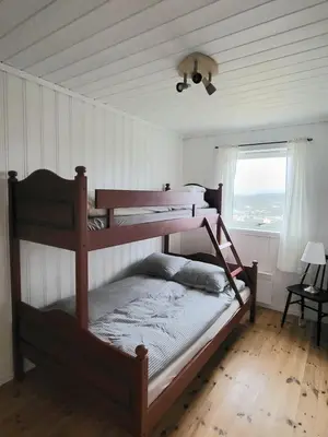 a bedroom with two bunk beds and a window at Stor hytte med fantastisk utsikt in Vikso