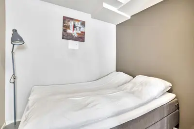 a white bed in a room with a lamp at Bryggen Nest in Bergen