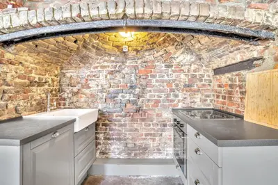 a kitchen with a brick wall and white cabinets at Bryggen Nest in Bergen