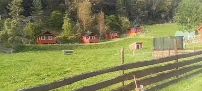 a group of cabins in a field with a fence at Vassel gård in Herand
