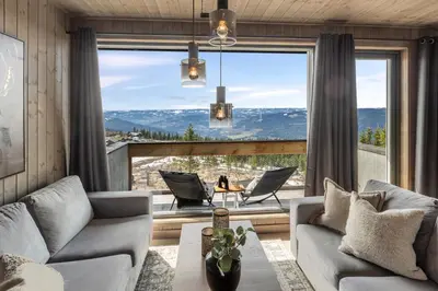 a living room with a couch and chairs and a large window at New modern apartment with ski in out in Hafjell in Hafjell