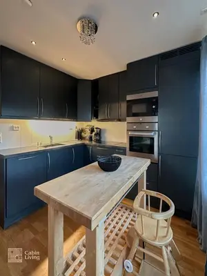 a kitchen with blue cabinets and a wooden table at Modern apartment Hovden ski in-out x-skiing, 2 bathrooms and balcony in Hovden