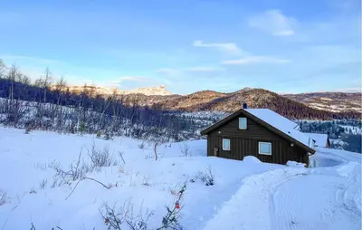 a small cabin in the snow with mountains in the background at Moderne Hytte Midt I Skibakken in Ryfoss