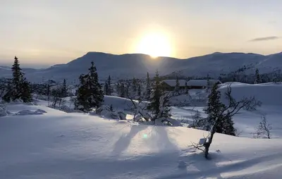 a snow covered hill with the sun in the distance at Stunning Home In Flå With Sauna in Skadeland