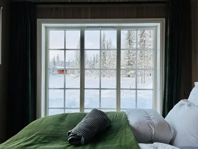 a bedroom with a large window with snow outside at Beitobygda Getaway ,Nature And Luxury in Beitostøl