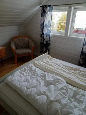 a bed in a room with a chair and a window at Ski WM Trondheim in Melhus