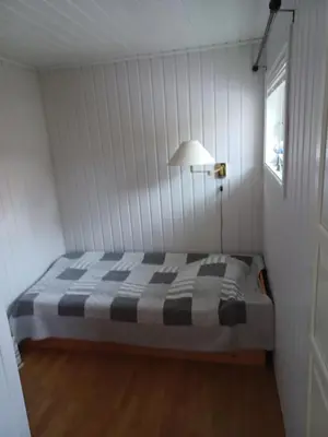 a bedroom with a bed and a lamp and a window at Ski WM Trondheim in Melhus