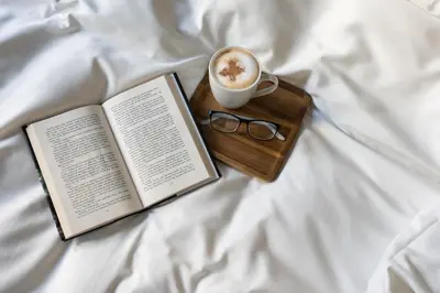 a book and a cup of coffee sitting on a bed at VANDER Altona in Bergen