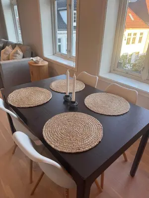 a dining room table with four chairs and candles on it at Sentrumsnær trivelig leilighet in Bergen