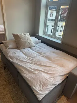 an unmade bed in a bedroom with a window at Sentrumsnær trivelig leilighet in Bergen