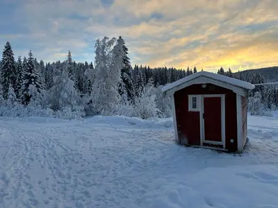 a smallshed in a snow covered field with trees at Turifoss Camping Cabin 1 in Meråker